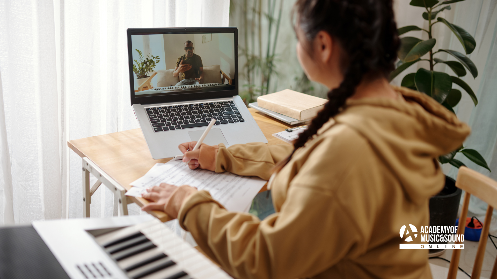 Person sat at desk with a laptop in front of them learning music online.