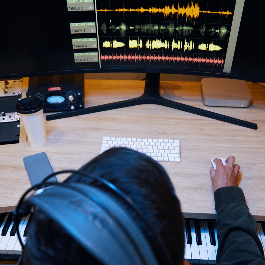 Person sat at desk with headphones on working on music project. They're a music student who's applied through Clearing and can study at home.