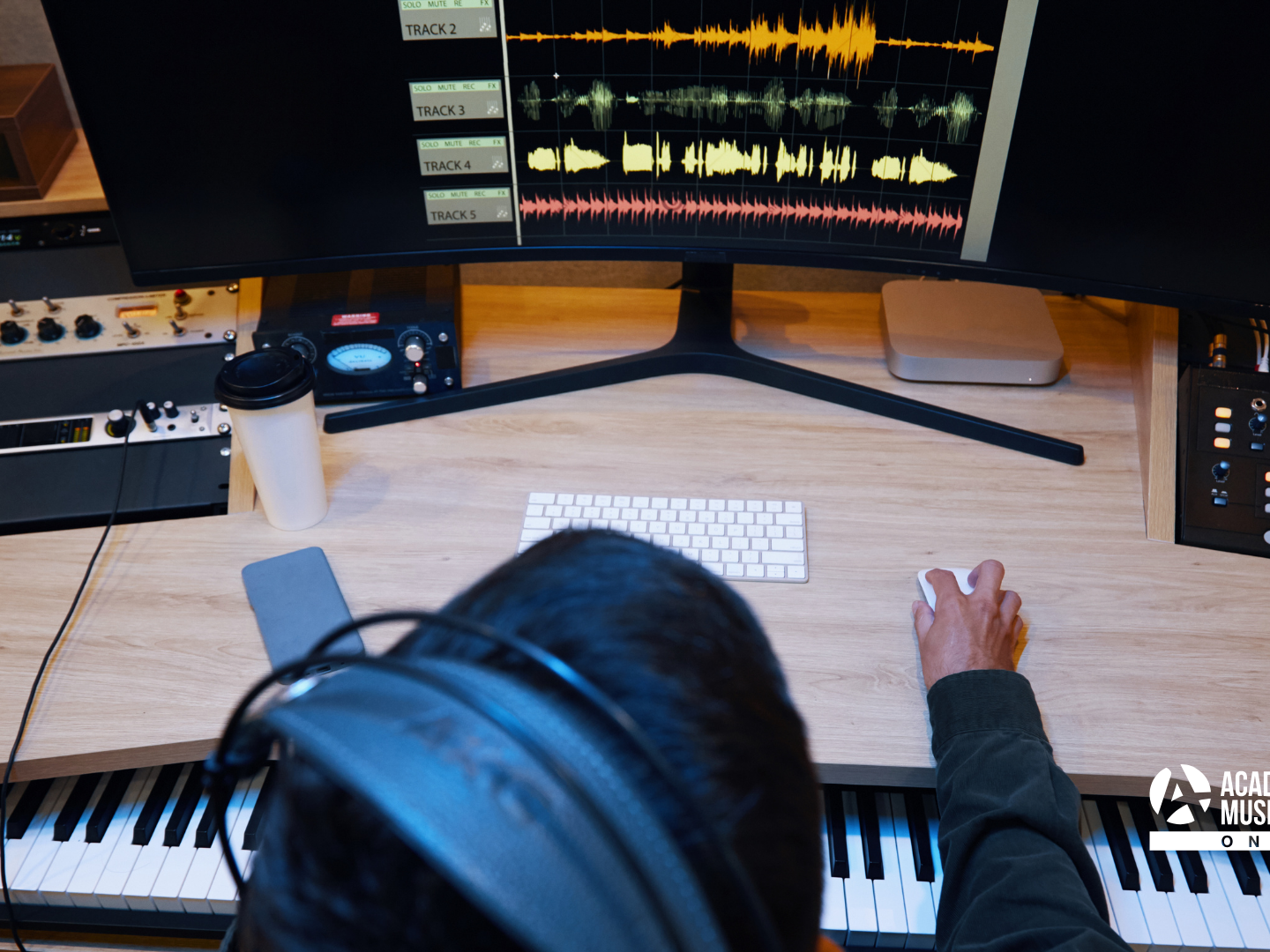 Person sat at desk with headphones on working on music project. They're a music student who's applied through Clearing and can study at home.