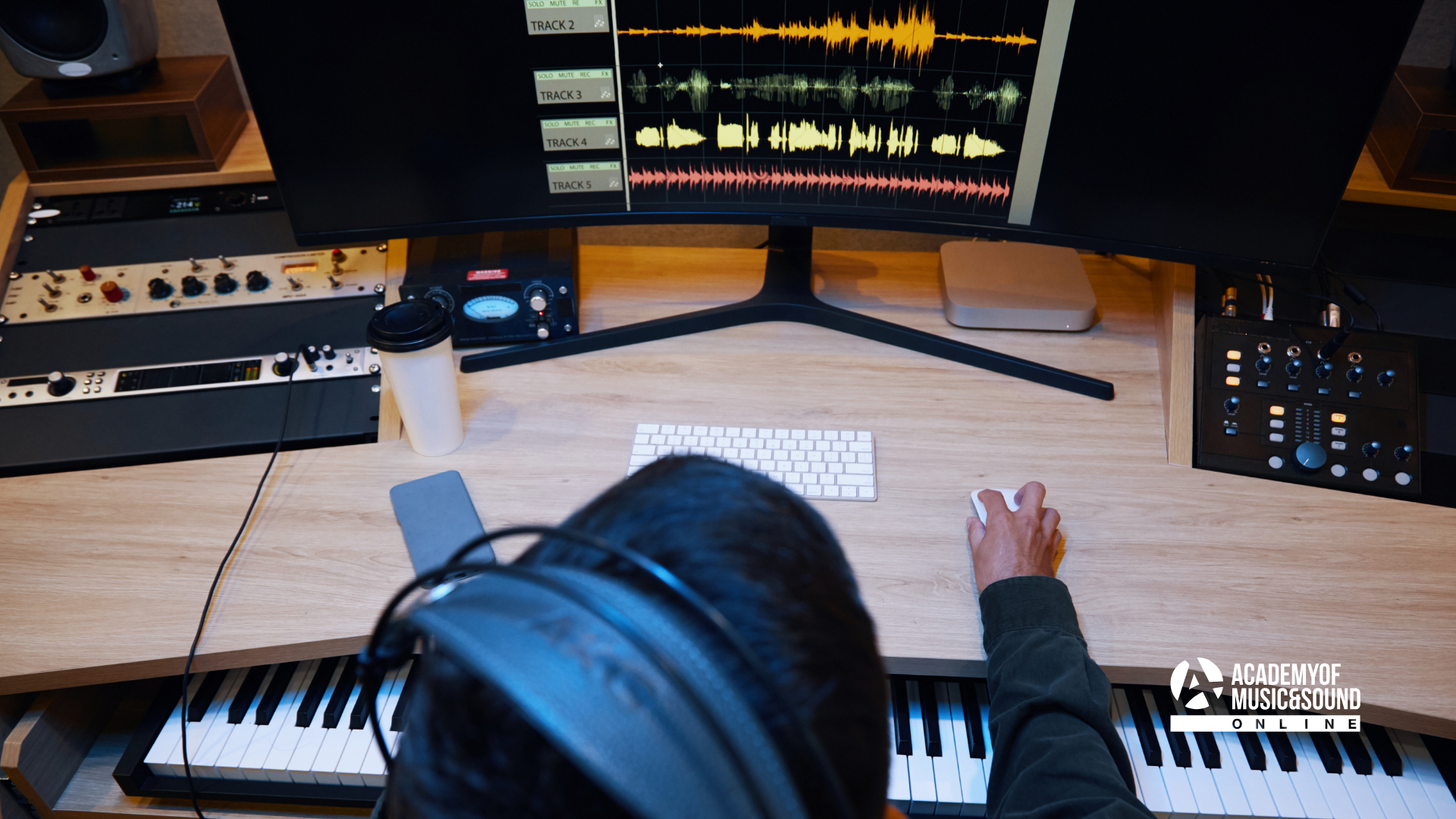 Person sat at desk with headphones on working on music project. They're a music student who's applied through Clearing and can study at home.